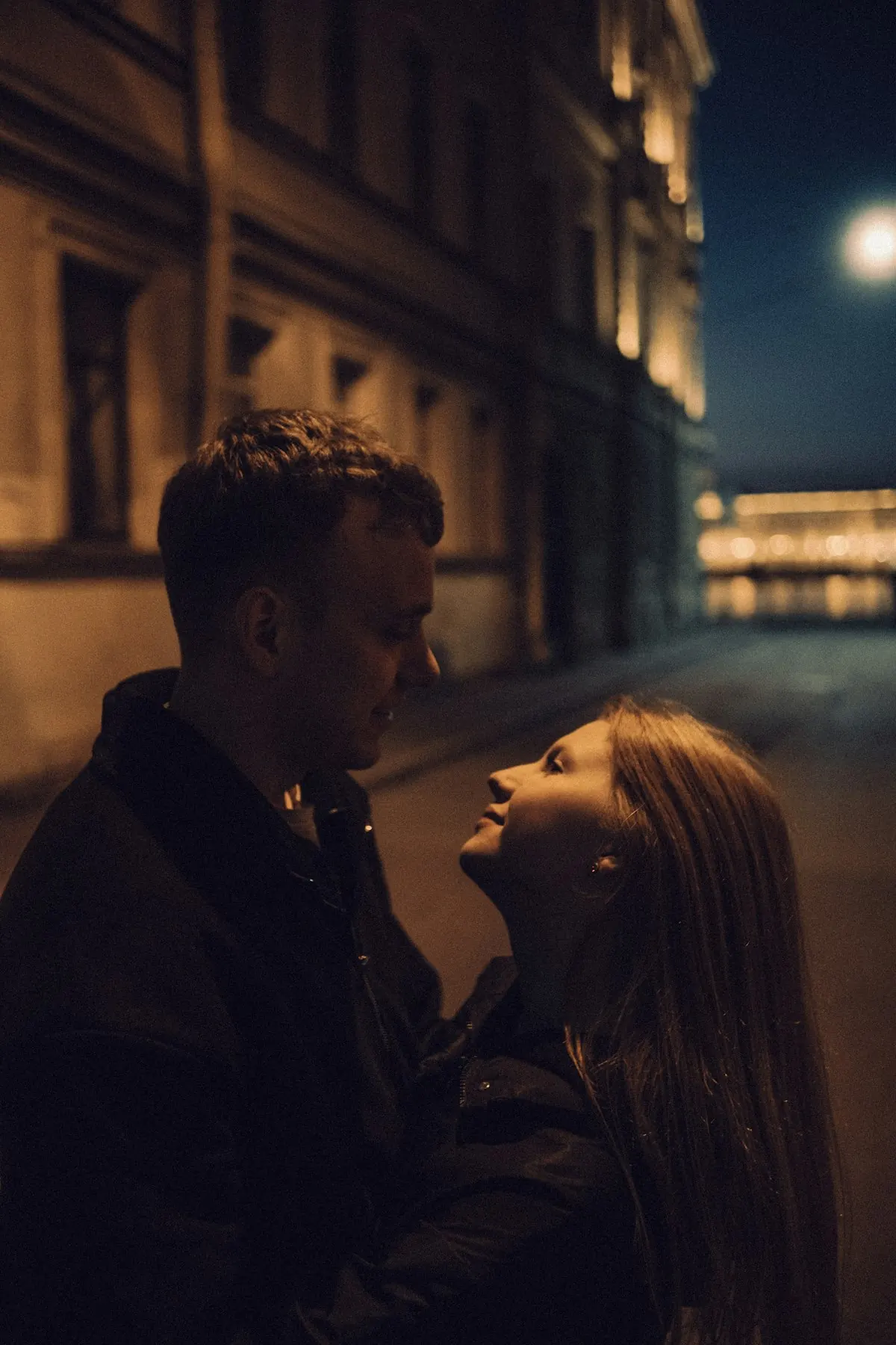 Casal abraçado numa rua iluminada à noite