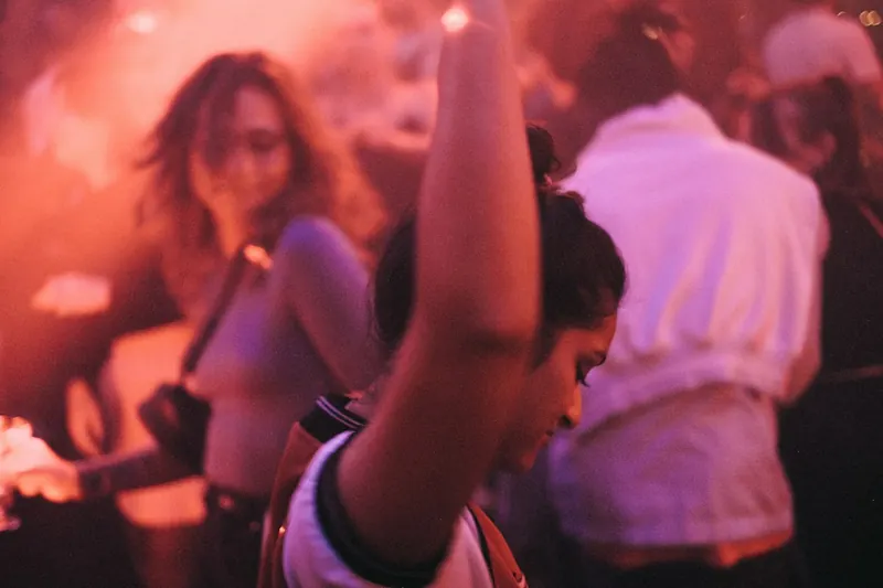 Gente dançando numa festa com luz rosa