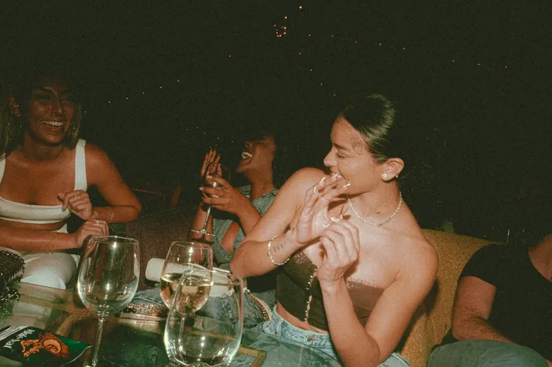 Amigas rindo à mesa com taças, foto com flash